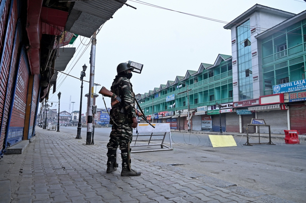 A security personnel stands guard to block a road near closed shops while strict restrictions are imposed during a lockdown in Srinagar on September 28, 2019. / AFP / Tauseef MUSTAFA