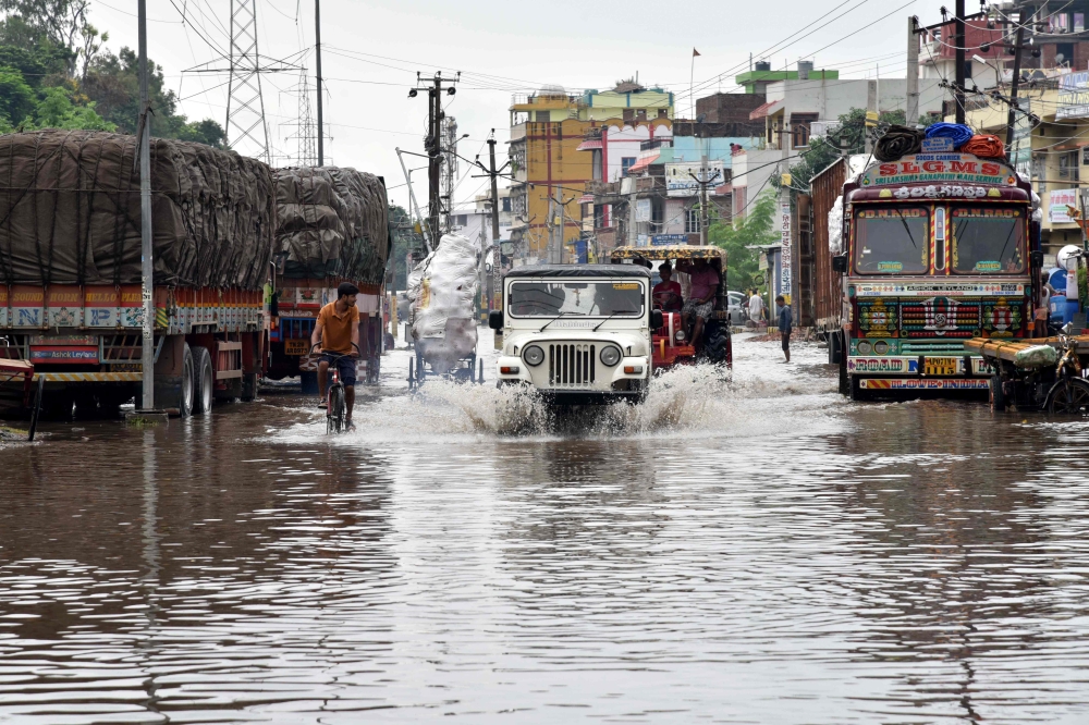 Commuters make their way on a waterlogged road following heavy rainfalls in Patna on September 30, 2019. / AFP / Sachin KUMAR 