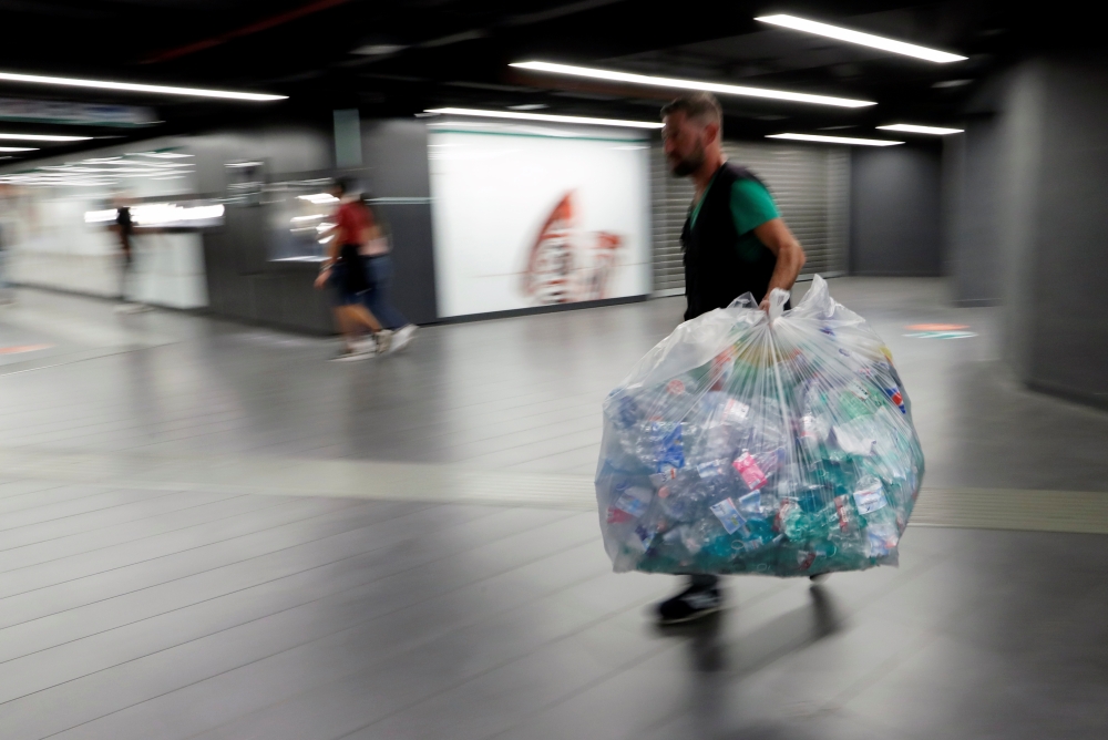 A worker walks as he holds a big plastic bag full of plastic bottles in San Giovanni metro station in Rome, Italy September 27, 2019. Reuters/Remo Casilli