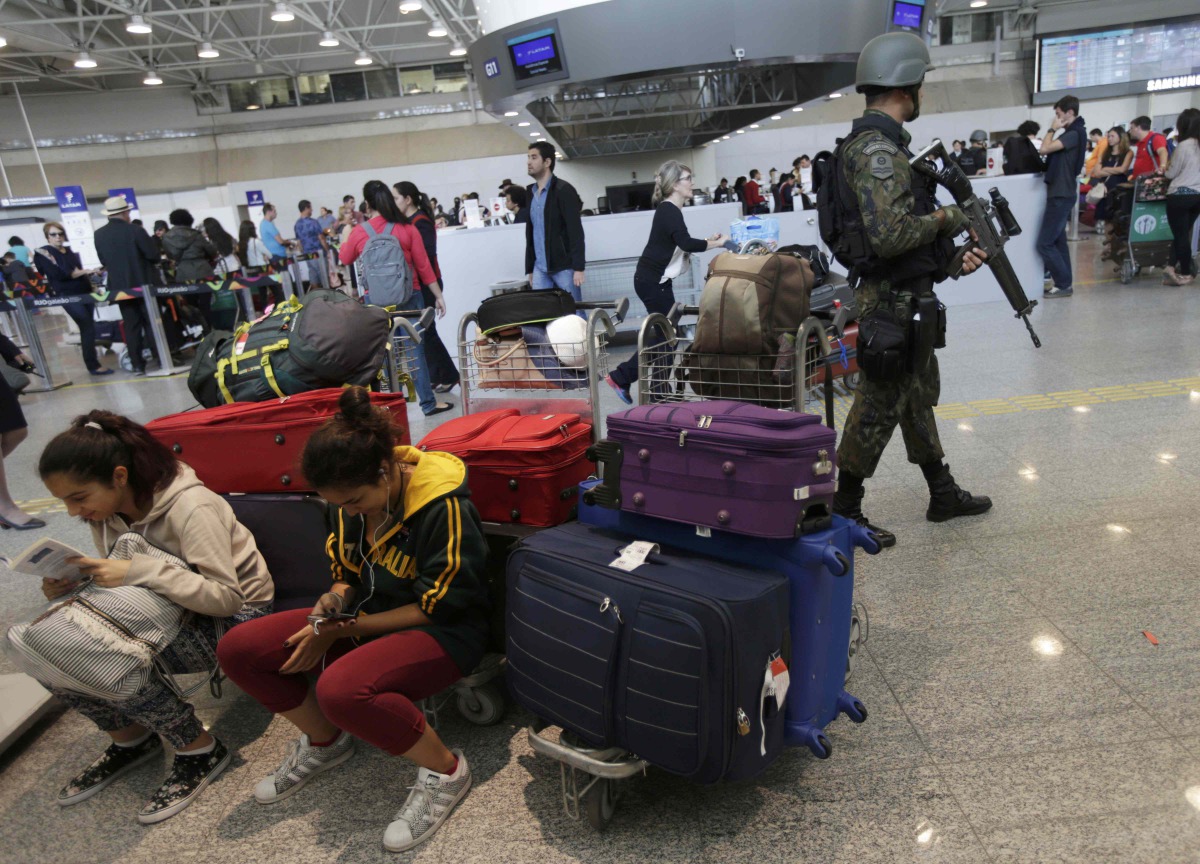 A Brazilian soldier patrols past travelers in the Galeao international airport in Rio de Janeiro, July 24, 2016. Reuters/Ricardo Moraes
 