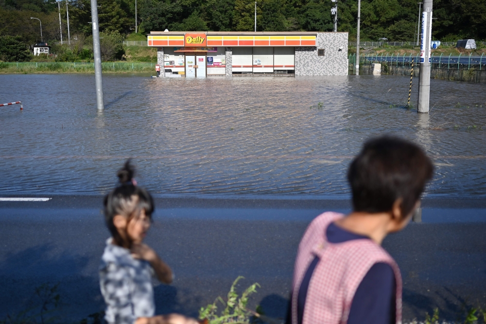 People walk by a flooded convenience store in the aftermath of Typhoon Hagibis in Kakuda, Miyagi Prefecture on October 13, 2019. AFP / CHARLY TRIBALLEAU