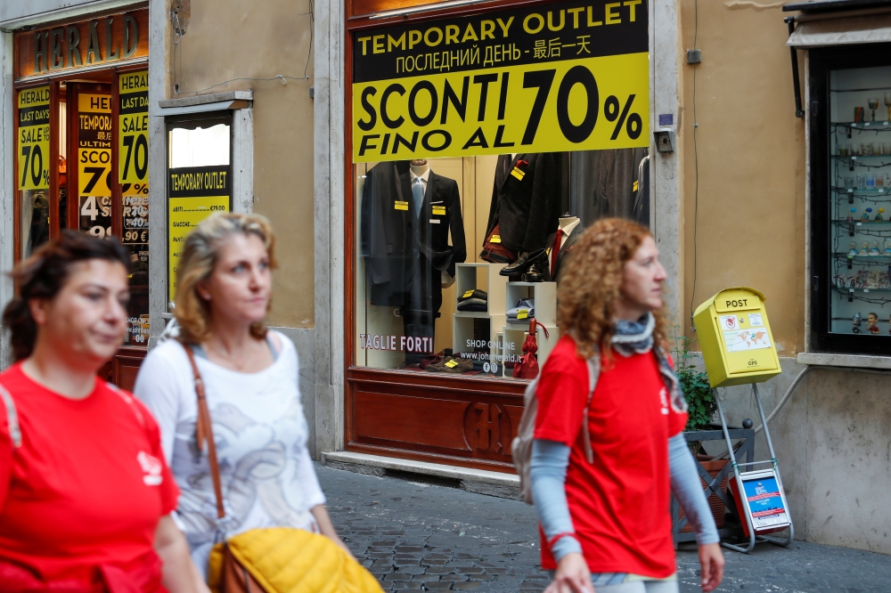 People walk in front of a shop in downtown Rome as Italy's cabinet prepares to approve a 2020 budget draft before sending the document to Brussels for scrutiny by the European Commission, Rome, Italy, October 15 2019. REUTERS/Remo Casilli