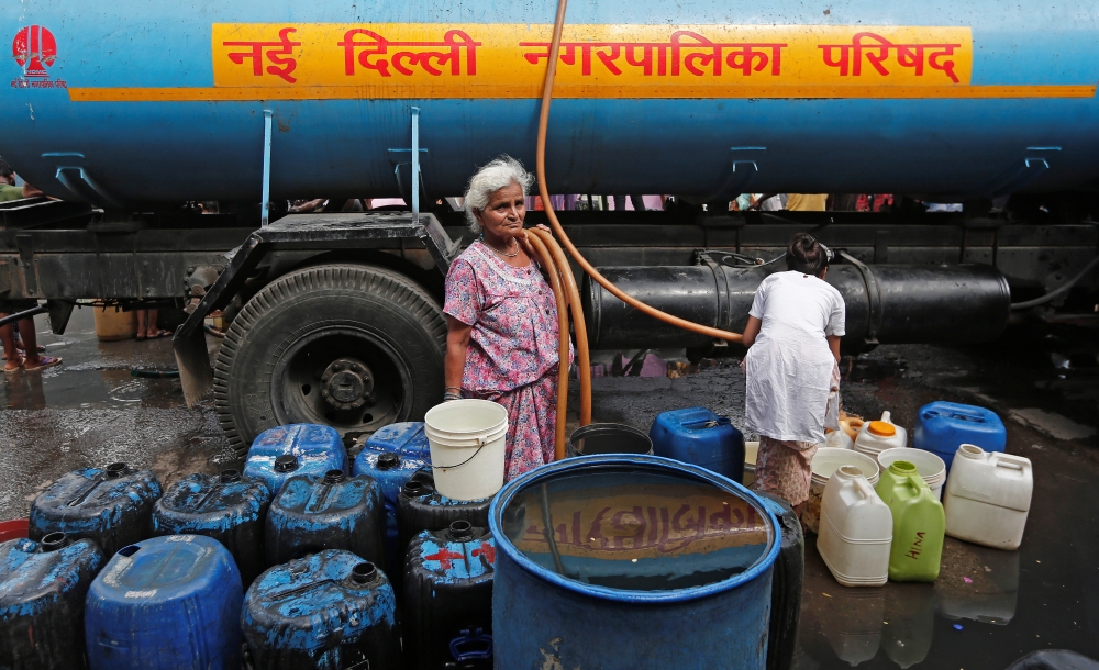A woman stands after filling her containers with drinking water from a municipal tanker in New Delhi, India, June 28, 2019. Reuters / Adnan Abidi