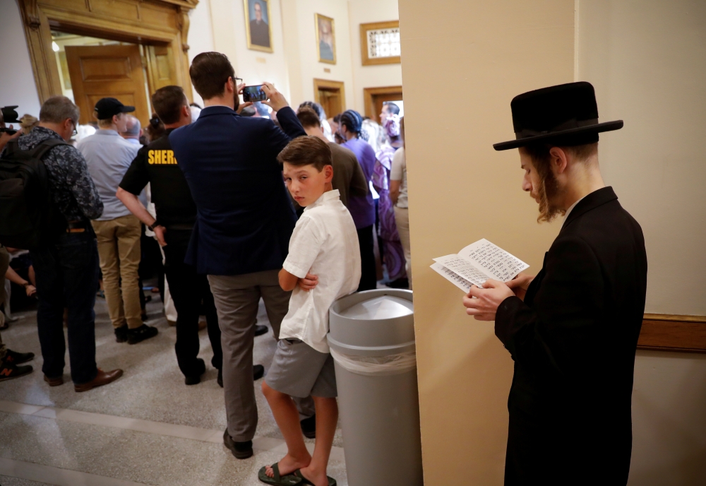 An Orthodox Jewish man supporting a religious exemption to childhood vaccinations pauses to pray in a hallway inside New York State Supreme Court during a hearing challenging the constitutionality of the NY State Legislature's repeal of the religious exem