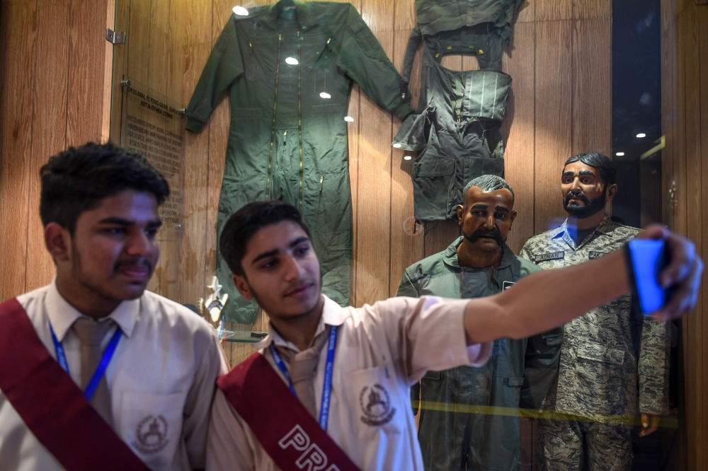 Students take a selfie in front of the statue of Indian pilot Wing Commander Abhinandan Varthaman (2R) whose plane was shot down over Kashmir earlier this year, put on display at Pakistan Air Force Museum in Karachi on November 12, 2019. AFP / Asif Hassan
