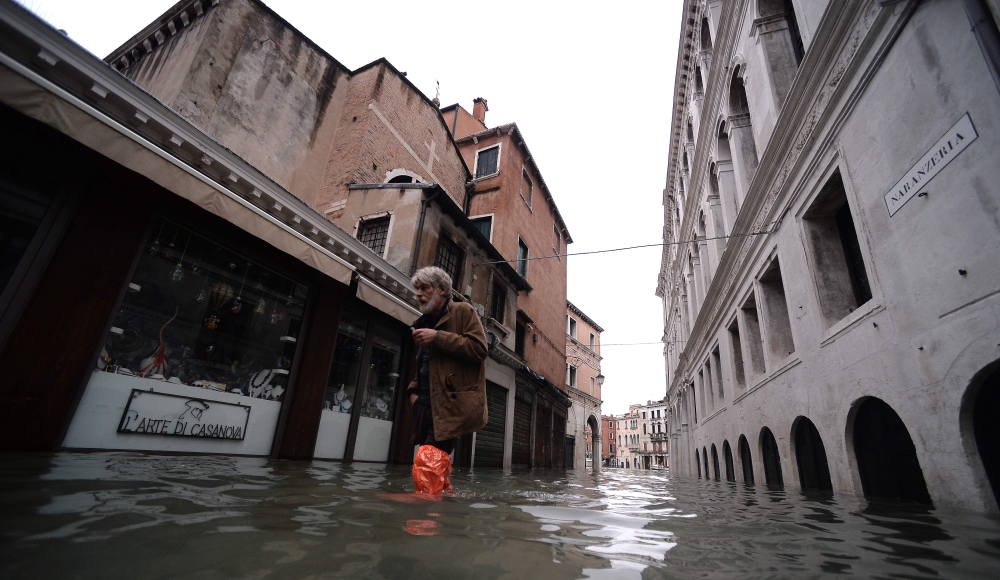 A man walks in a flooded street in Venice, during 