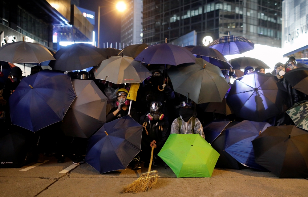 Protesters hide behind umbrellas during a Human Rights Day march, organised by the Civil Human Right Front, in Hong Kong, China December 8, 2019. Picture taken with a long exposure. REUTERS/Danish Siddiqui