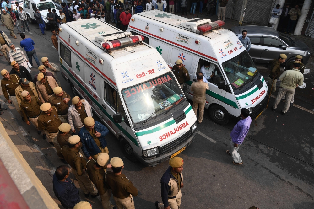 Police personnel and ambulances are seen along a road following a factory fire in Anaj Mandi area of New Delhi on December 8, 2019  / AFP / Sajjad HUSSAIN