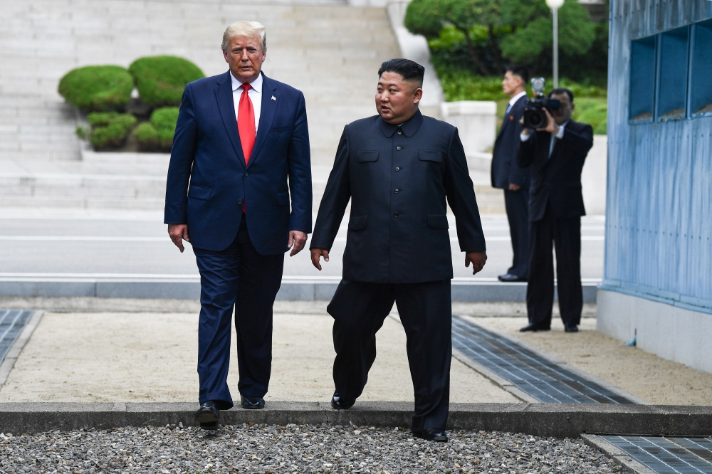 (FILES) In this file photo taken on June 30, 2019, North Korea's leader Kim Jong Un and US President Donald Trump cross south of the Military Demarcation Line that divides North and South Korea, after Trump briefly stepped over to the northern side, in th