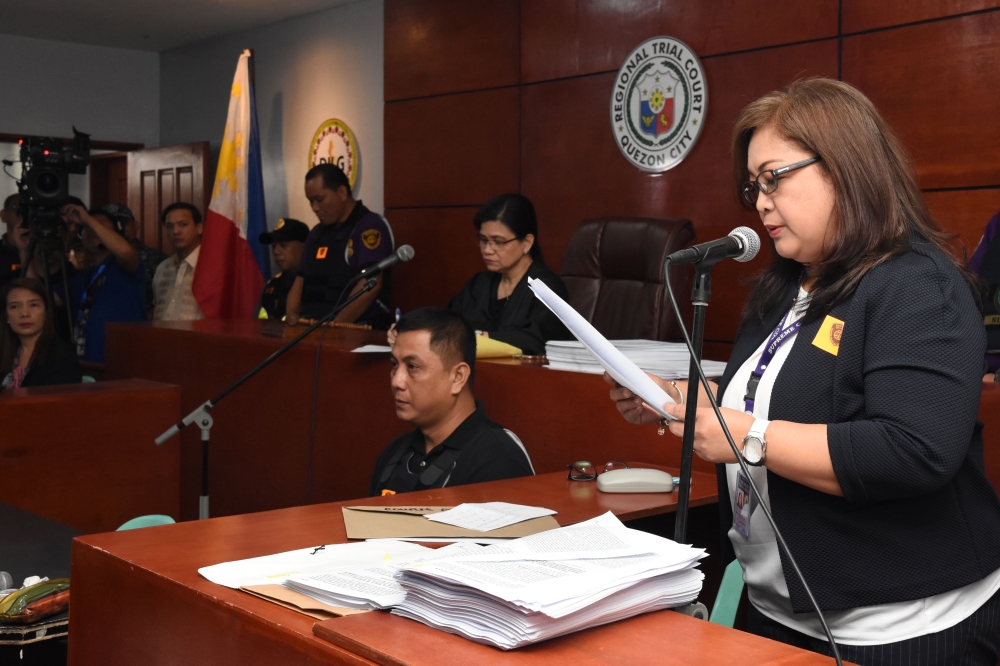 This handout from the Supreme Court - Public Information Office (SC-PIO) taken and released on December 19, 2019, shows a court employee (R) reading the verdict for the 2009 Maguindanao massacre at the trial venue inside a prison facility in Manila. AFP P