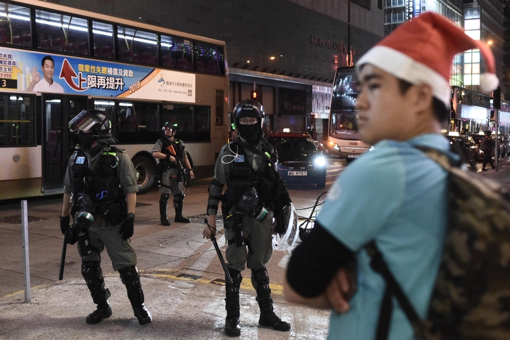 A man with a Santa hat stands in front of riot police during a protest in Mong Kok district in Hong Kong on December 25, 2019. AFP / Philip Fong
 
 