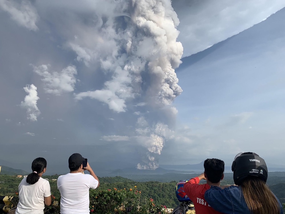  People take photos of a phreatic explosion from the Taal volcano as seen from the town of Tagaytay in Cavite province, southwest of Manila, on January 12, 2020. / AFP / Bullit MARQUEZ