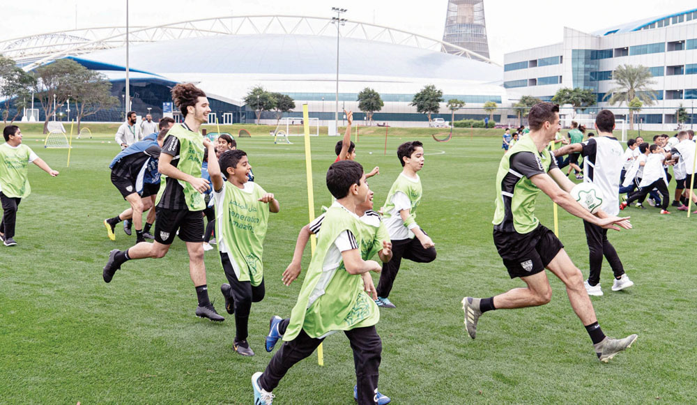 Schoolchildren train with players of Belgian football club KAS Eupen and Generation Amazing officials at Aspire Academy, Doha. 