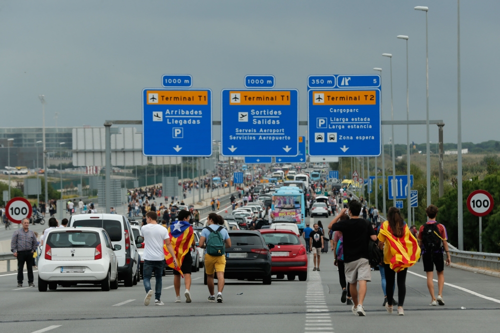 People walk on the highway towards El Prat airport in Barcelona on October 14, 2019 as protesters took to the streets over a Supreme Court verdict. AFP / Pau Barrena