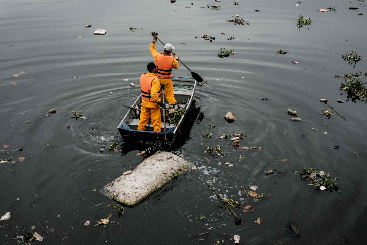 Cleaning staffers collect a bed mattress at the mouth of the Meriti river in Duque de Caxias next to Rio de Janeiro, July 20, 2016. AFP