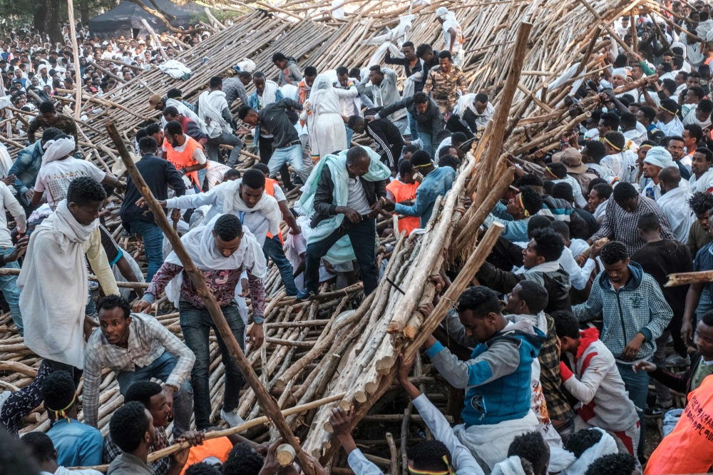 A crowd removes scaffoldings of a structure that collapsed, trapping and injuring dozens of people, during the celebration of Timkat, the Ethiopian Epiphany, in Gondar, Ethiopia, on January 20, 2020. AFP / Eduardo Soteras
 