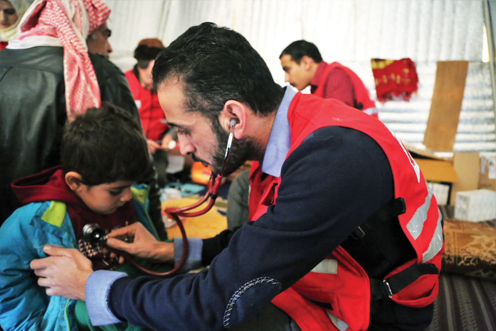 A doctor is checking a Syrian child under the program of QRCS for displaced people.