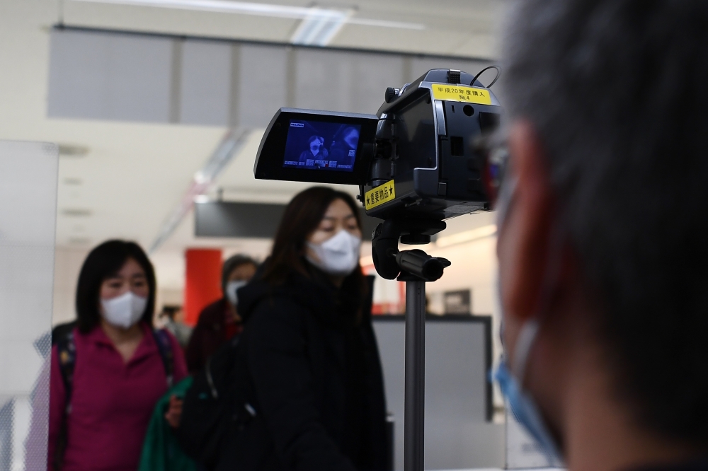 Passengers who arrived on one of the last flights from the Chinese city of Wuhan walk through a health screening station at Narita airport in Chiba prefecture, outside Tokyo, on January 23, 2020, as countries screen for anyone showing symptoms of a SARS-l