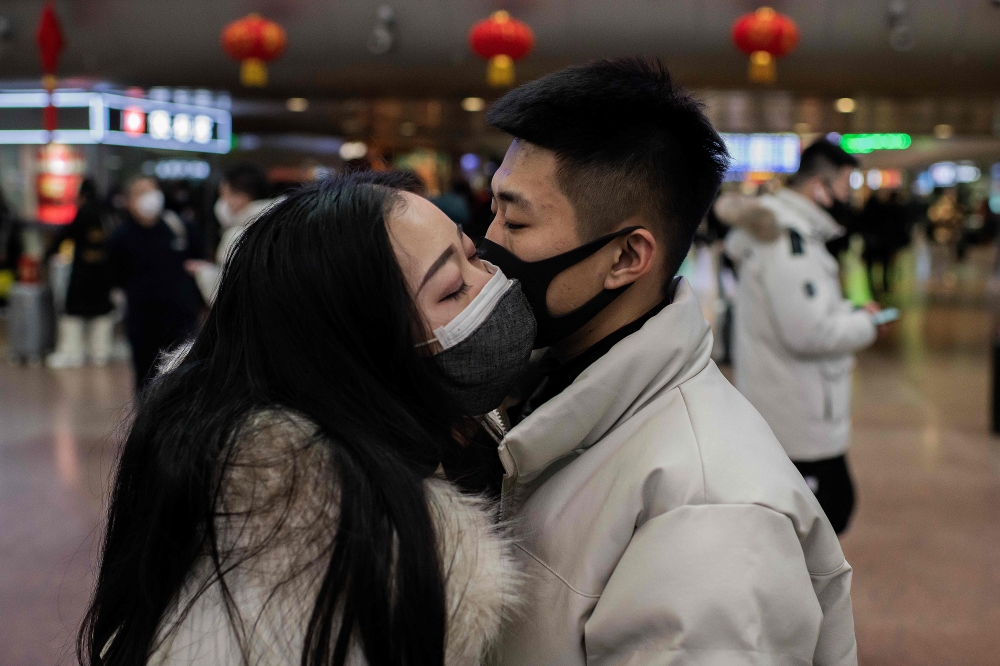 A couple, wearing protective masks, kisses goodbye as they travel for the Lunar New Year holidays, at Beijing West Railway Station in Beijing on January 24, 2020. AFP / Nicolas Asfouri
 
