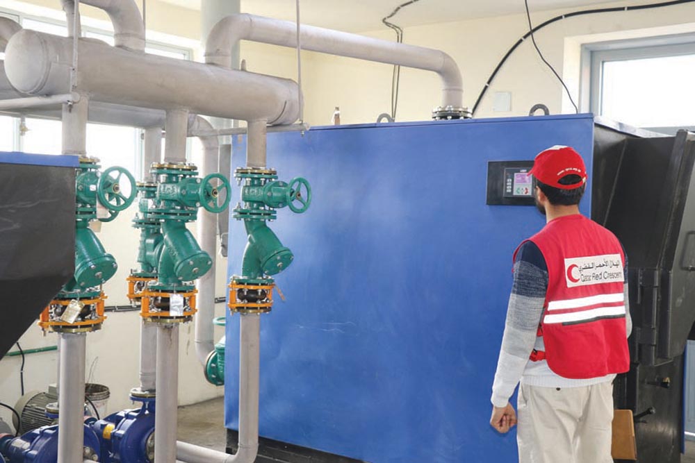A QRCS official stands next to  the new central heating system in Kabul.