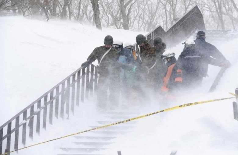 Rescue workers carry victims after an avalanche hit a group near a ski resort in Nasu town, north of Tokyo. Kyodo/via REUTERS

