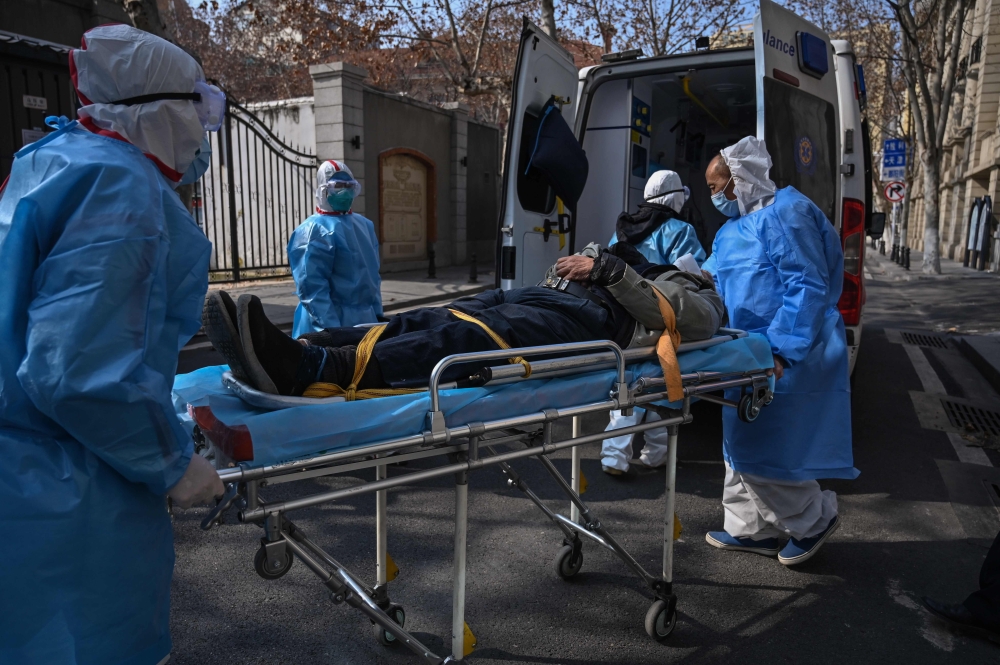 Medical staff in protective clothes are seen carrying a patient from an apartment suspected of having the virus in Wuhan, in Hubei province on January 30, 2020. AFP / Hector Retamal 