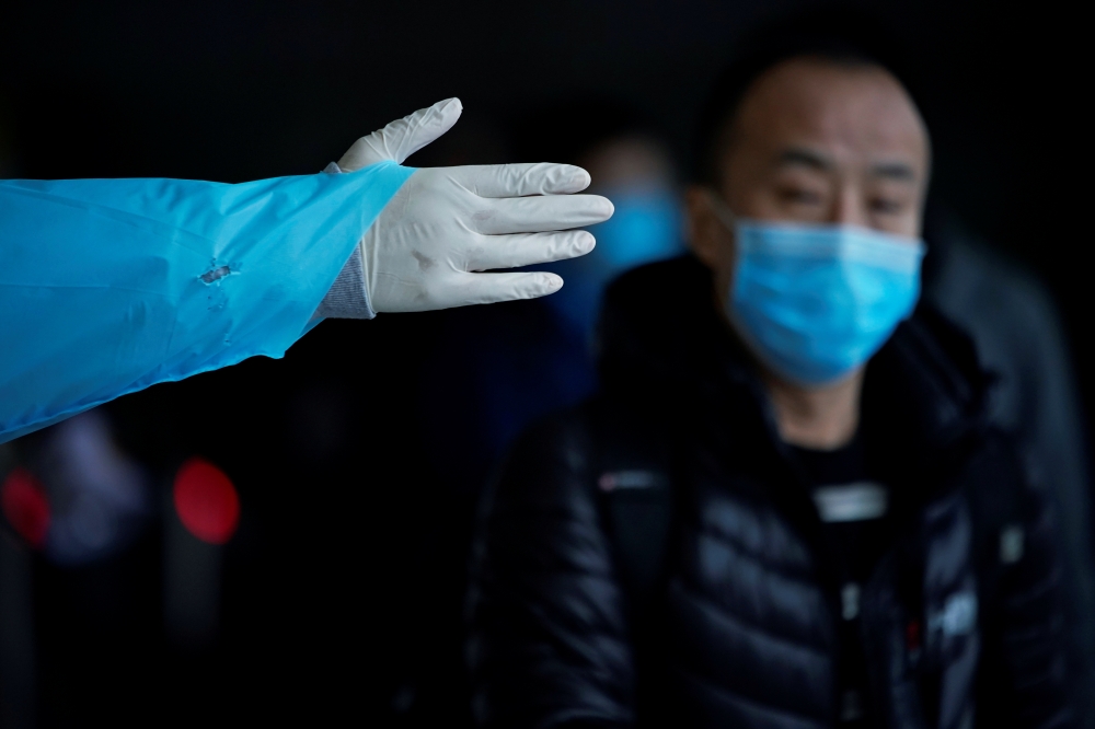 A passenger wearing a mask walk outside the Shanghai railway station in Shanghai, China, as the country is hit by an outbreak of the new coronavirus, February 8, 2020. REUTERS/Aly Song