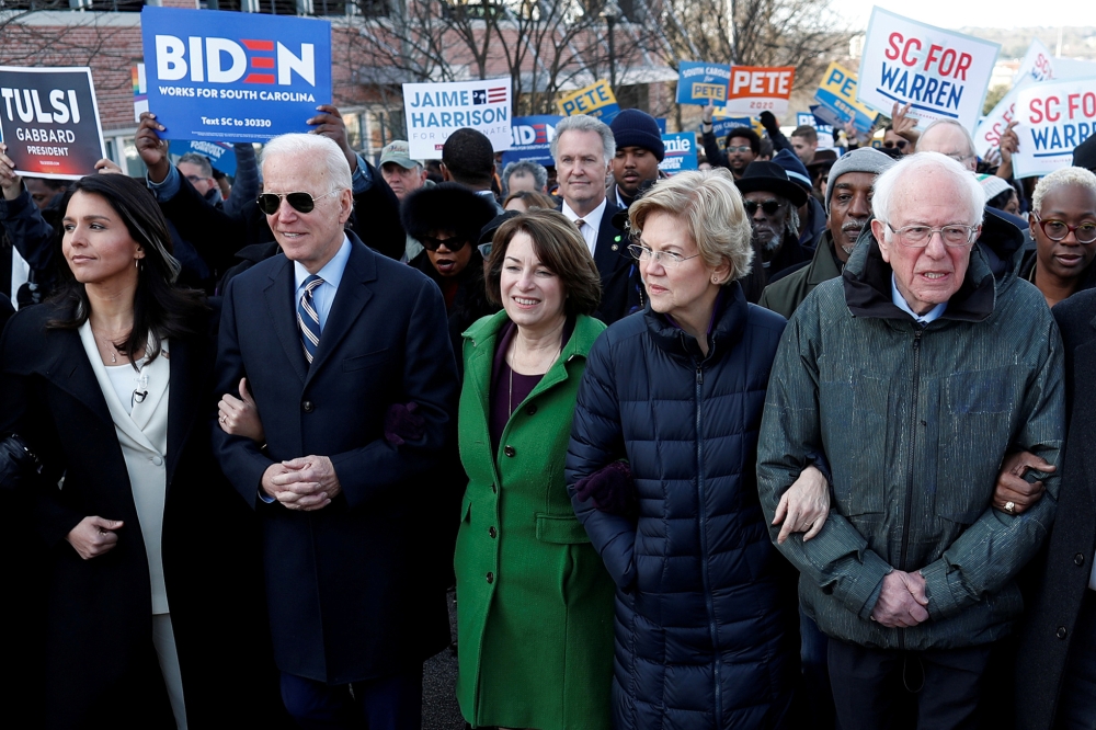 Tulsi Gabbard, Joe Biden, Amy Klobuchar, Elizabeth Warren and Bernie Sanders, walk arm-in-arm with during the MLK Day Parade in Columbia January 20, 2020. Reuters / Randall Hill