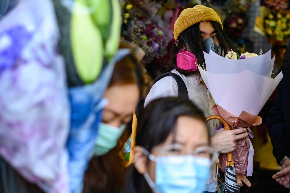 A man wearing a protective face mask as a preventative measure against the COVID-19 coronavirus, buys flowers to mark Valentine's Day in Hong Kong on February 14, 2020. / AFP / Philip Fong
