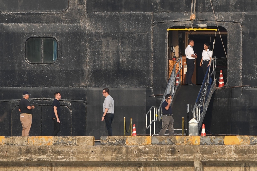 People stand near by the Westerdam cruise ship in Sihanoukville on February 18, 2020, where the liner on February 13 docked after being refused entry at other Asian ports due to fears of the novel coronavirus. A scramble intensified February 17 to trace p