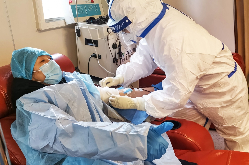 A person (L), who has recovered from the COVID-19 coronavirus infection, donates plasma in Zouping in China's eastern Shandong province on February 28, 2020, aimed at curing infected patients in severe and critical conditions./ AFP / STR