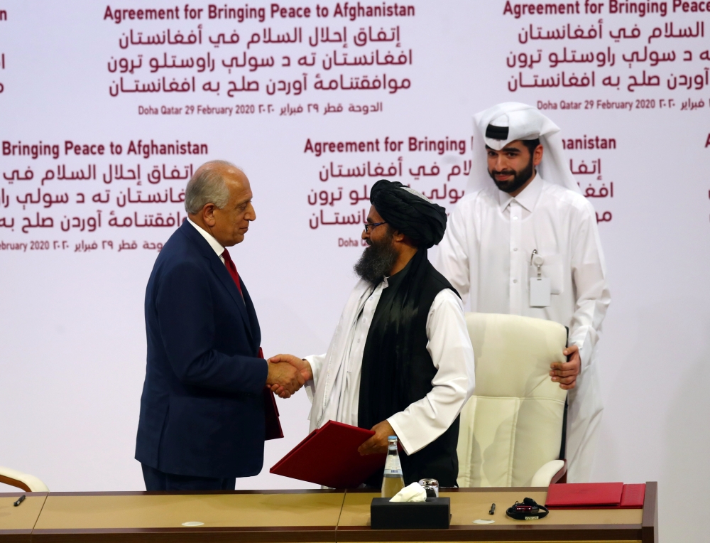 Mullah Abdul Ghani Baradar, the leader of the Taliban delegation, and Zalmay Khalilzad, U.S. envoy for peace in Afghanistan, shake hands after signing agreement at ceremony between members of Afghanistan's Taliban and the U.S. in Doha