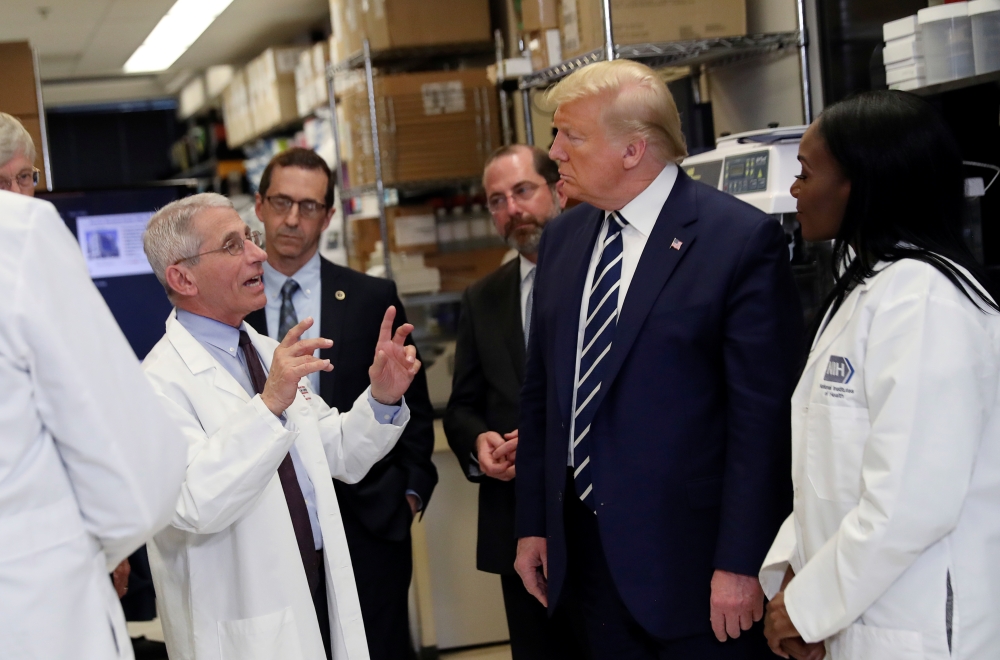 US President Donald Trump is flanked by Health and Human Services (HHS) Secretary Alex Azar and National Institutes of Health Doctor Kizzmekia Corbett, research fellow at the NIH Vaccine Research Center, as he listens to Director of National Institute of 