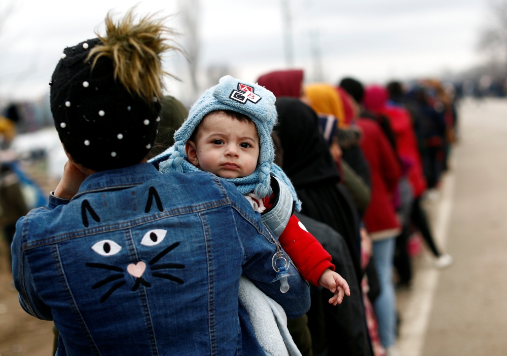 Migrants stand in line to receive food aid at Turkey's Pazarkule border crossing with Greece's Kastanies, near Edirne in Turkey, March 5, 2020. Reuters/Murad Sezer