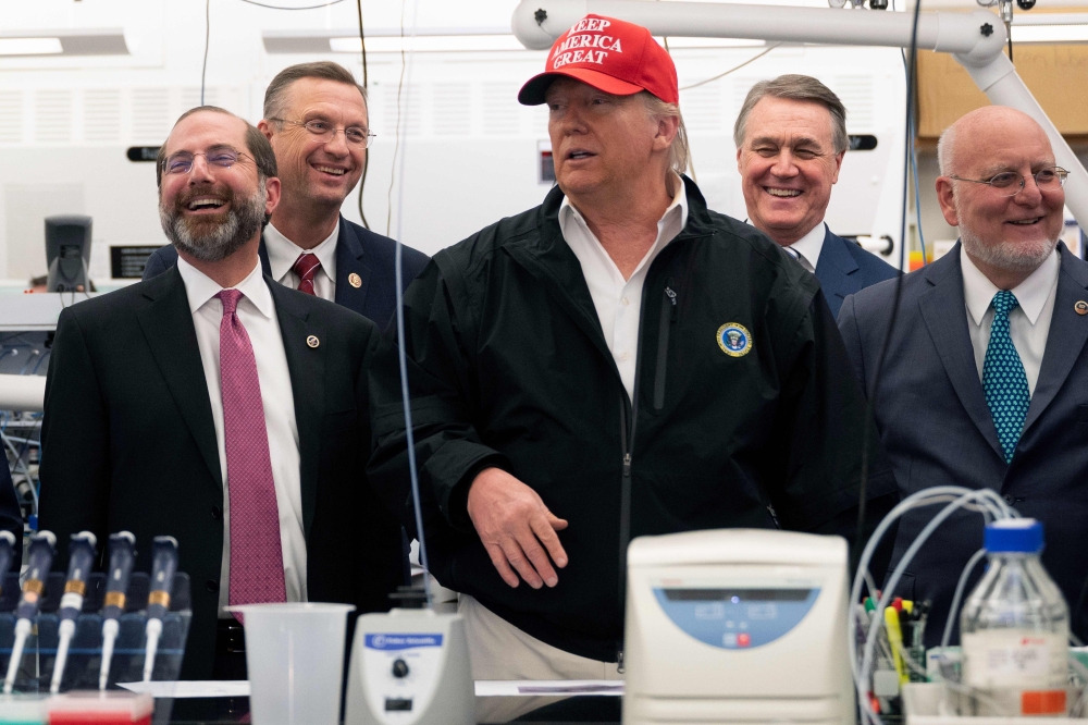 US President Donald Trump (C) gestures during a tour of the Centers for Disease Control and Prevention (CDC) as US Representative Doug Collins (2L) and US Health and Human Services Secretary Alex Azar (L) look on in Atlanta, Georgia, on March 6, 2020./ AF