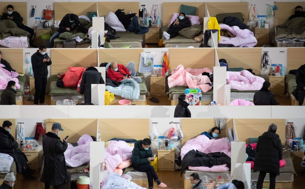 FILE PHOTO: Patients with mild symptoms of the COVID-19 coronavirus resting at night in the temporary Fangcai Hospital set up in a sports stadium in Wuhan, China, February 18, 2020. AFP