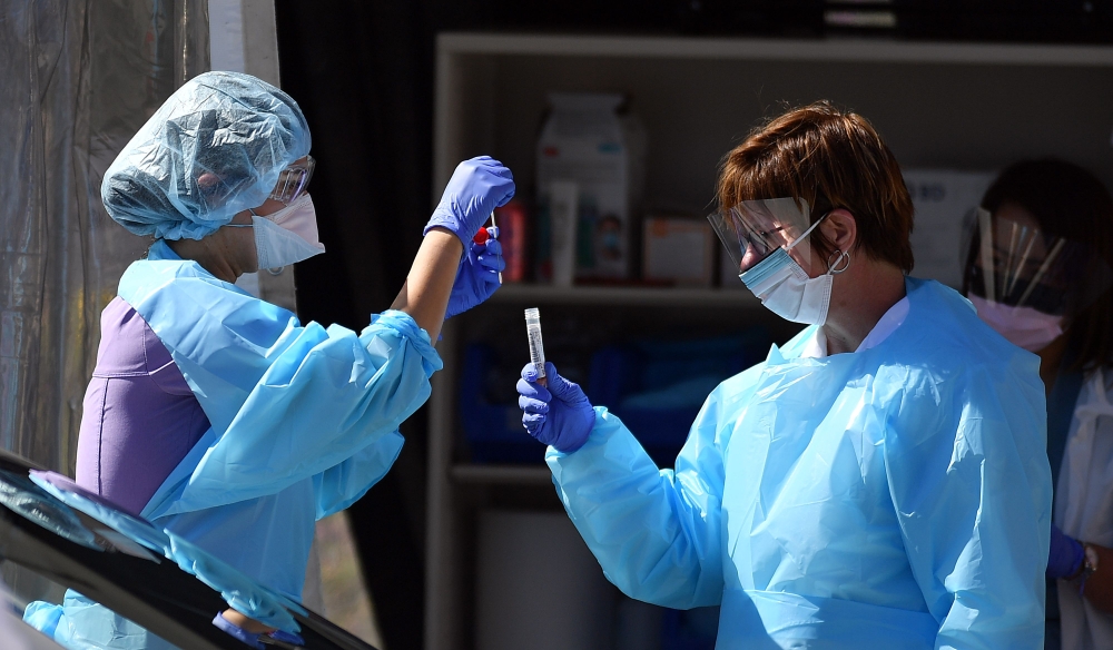Medical workers at Kaiser Permanente French Campus test a patient for the novel coronavirus, COVID-19, at a drive-thru testing facility in San Francisco, California on March 12, 2020.  / AFP / Josh Edelson 
