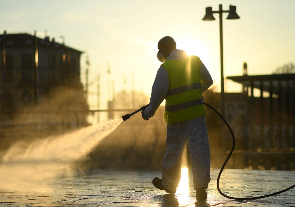 A worker sanitizes a street on the fourth day of an unprecedented lockdown across of all Italy imposed to slow the outbreak of coronavirus, in Milan, Italy, March 13, 2020. Reuters/Daniele Mascolo
 