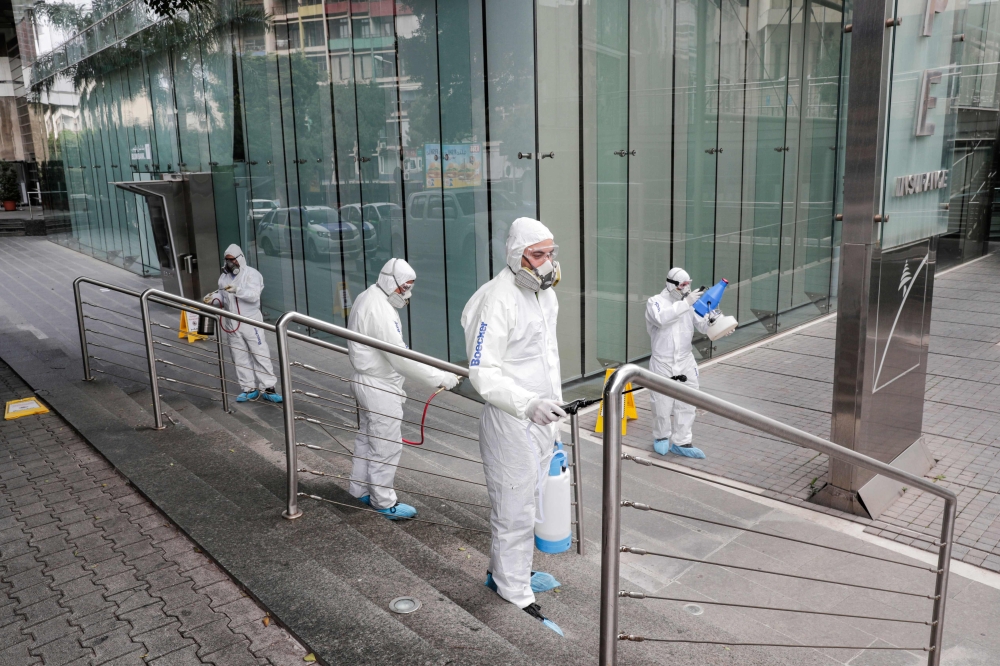 Employees of a private company spray sanitising liquid around a bank in a bid to limit the spread of the cornonavirus Civid-19, in the Lebanese capital Beirut on March 15, 2020. / AFP / ANWAR AMRO
