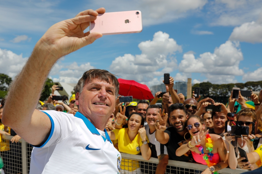 Brazilian President Jair Bolsonaro takes a selfie with supporters in front of the Planalto Palace, after a protest against the National Congress and the Supreme Court, in Brasilia, on March 15, 2020. / AFP / Sergio LIMA 