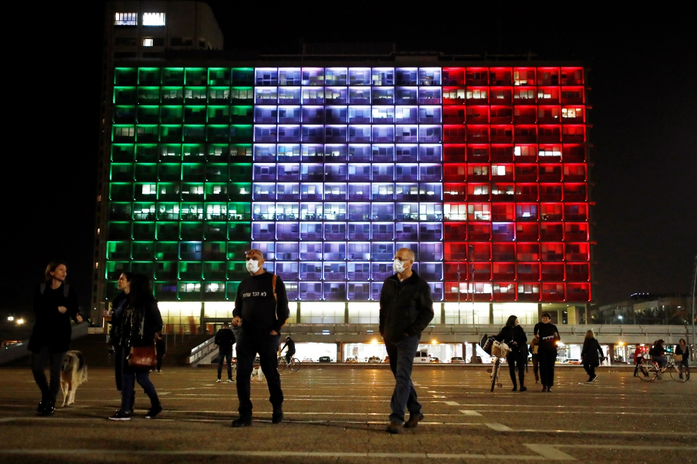  People walk at Rabin square as the municipality building is lit in the colours of the Italian flag in solidarity with the coronavirus situation, in Tel Aviv, Israel March 15, 2020 REUTERS/ Corinna Kern 