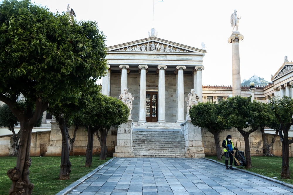 ATHENS - Greece, MARCH 17: A cleaner sweeps with a protective mask as a preventive measure against coronavirus (COVID-19) outbreak in front of the central building of University of Athens in Greece on March 17, 2020. ( Andreas Papakonstantinou - Anadolu A