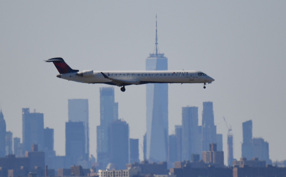 (FILES) In this file photo taken on March 15, 2020 A plane from Delta airline is seen above the skyline of Manhattan before it lands at JFK airport in New York City. AFP / Johannes EISELE