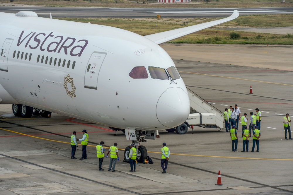 Groundsmen stand near the Vistara Boeing 787-9 displayed at the Wings India 2020 international exhibition at Begumpet Airport in Hyderabad, on March 14, 2020. / AFP / NOAH SEELAM