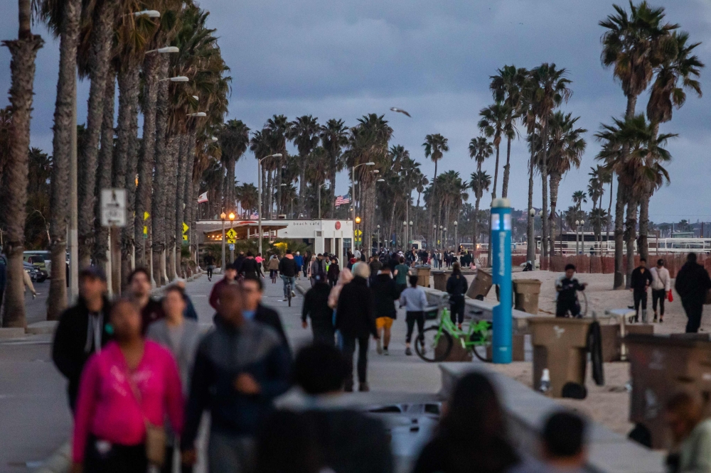 People walk on the beach twenty minutes after the California Governor Gavin Newson issued a statewide order to people stay home in Santa Monica, California on March 19, 2020. / AFP / Apu GOMES