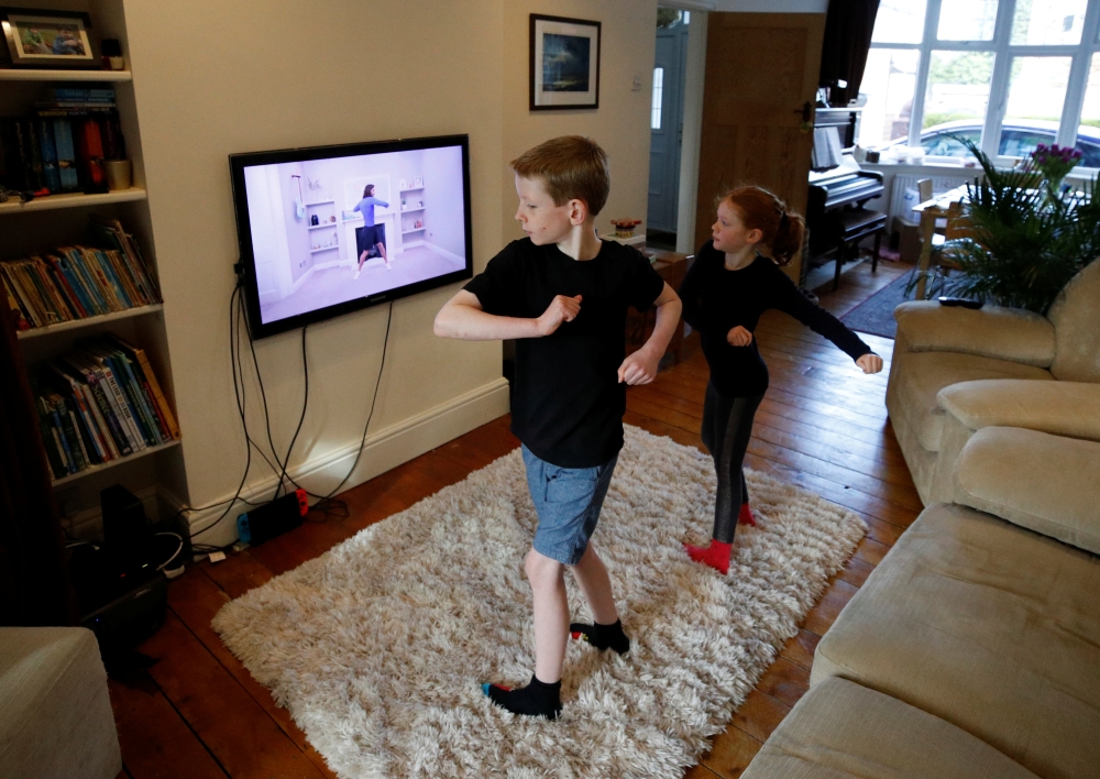 Alice and Joseph Wilkinson take part in a YouTube P.E. class at their home in Manchester, as the spread of the coronavirus disease (COVID-19) continues, in Manchester, Britain, March 23, 2020. REUTERS/Phil Noble