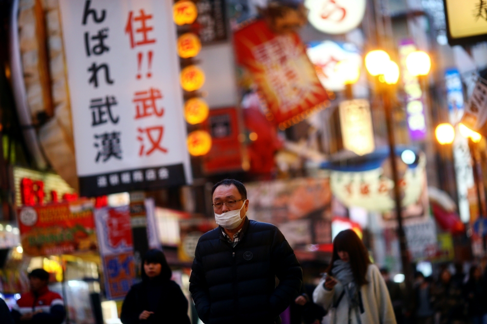 A man, wearing protective mask following an outbreak of the coronavirus disease (COVID-19), walks on an almost empty street in the Dotonbori entertainment district of Osaka, Japan, March 14, 2020. Pictured taken March 14, 2020. REUTERS/Edgard Garrido