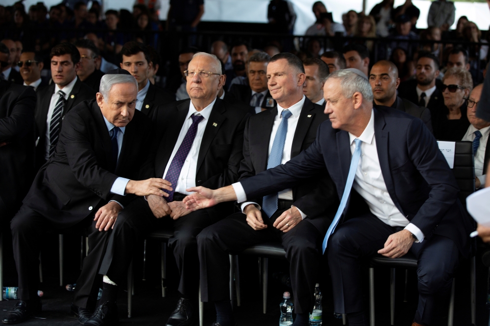 Head of Israel's Blue and White Party Benny Gantz and Israeli Prime Minister Benjamin Netanyahu shake hands as they attend a memorial ceremony for the late prime minister Yitzhak Rabin at Mount Herzl military cemetery in Jerusalem as Israel marks the 24th