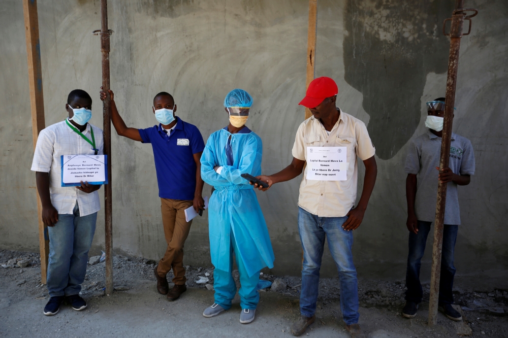 Medical staff display signs after the director of the hospital, surgeon Jerry Bitar, was kidnapped, as Haiti battles COVID-19 outbreak amid a spike in gang violence, in Port-au-Prince, Haiti March 27, 2020. The sign on right says the hospital will reopen 