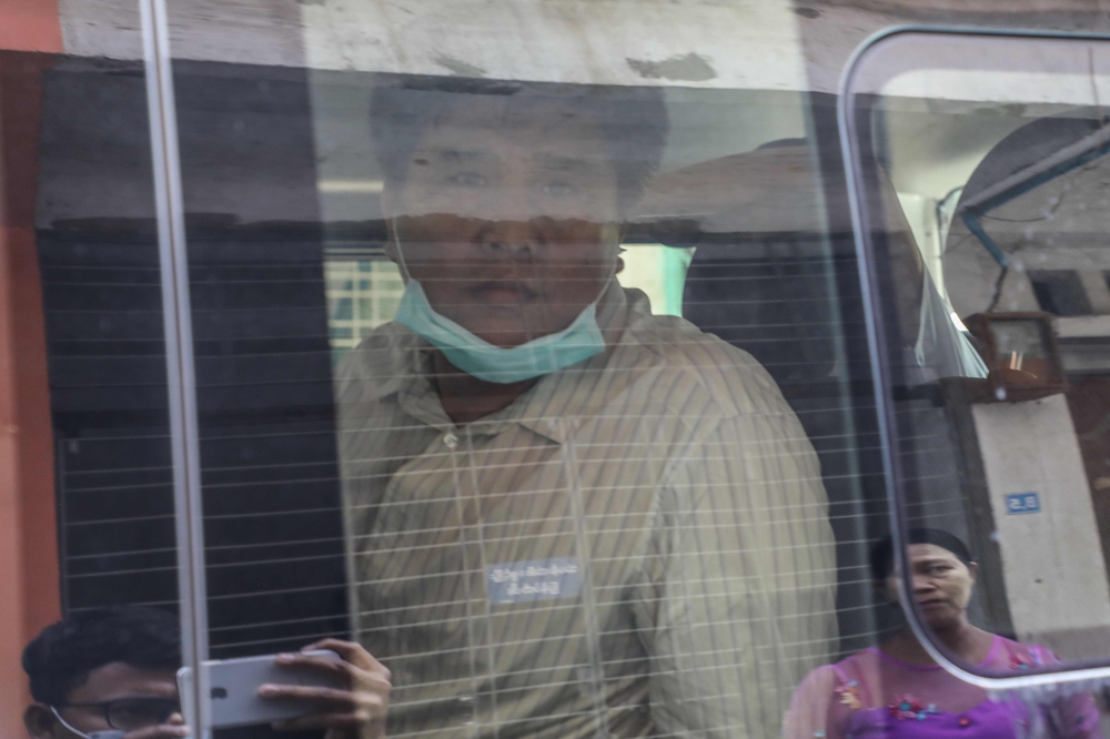Voice of Myanmar (VOM) editor-in-chief Nay Myo Lin (C) sits in a vehicle as he is escorted from his home by the police to court in Mandalay on March 31, 2020. / AFP / Zaw Zaw
